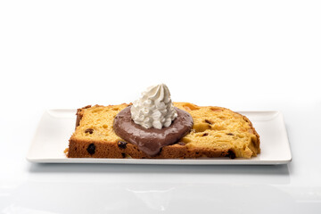 Slice of panettone with chocolate and milk cream on the white rectangular plate, typical Italian dessert for Christmas from Milan, isolated on white background