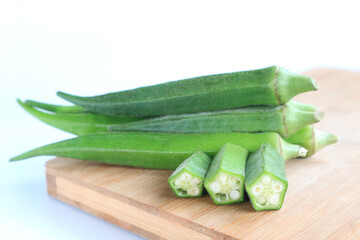 Fresh vegetable okra on wooden tray on white background       