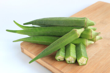 Fresh vegetable okra on wooden tray on white background       