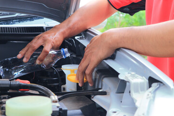 Man refills windshield wiper water on a car.