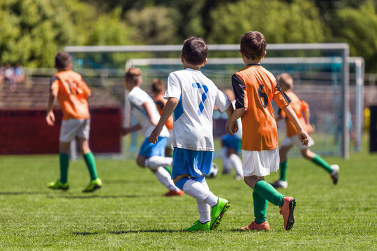 Boys playing in a soccer match. Football youth players kicking football ball in sunny day. Football competition tournament for school kids. Elementary age kids in white and orange sportswear