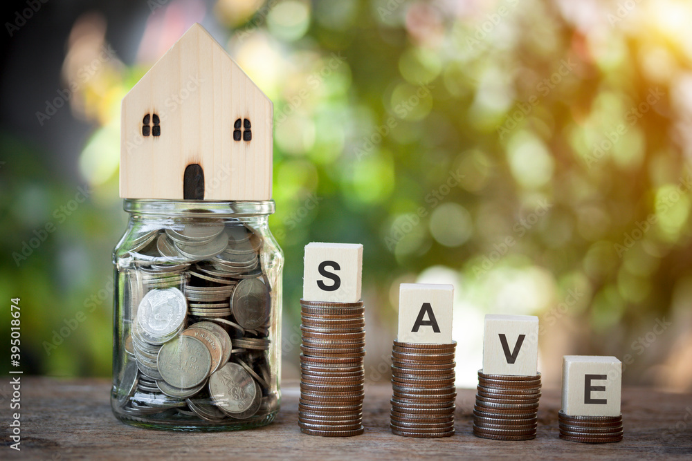 Poster stacking of coins and a glass jar with house model on top, wood concept save on coins show idea save