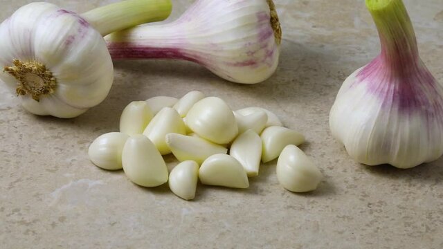 Fresh peeled garlic cloves with whole bulbs in the background