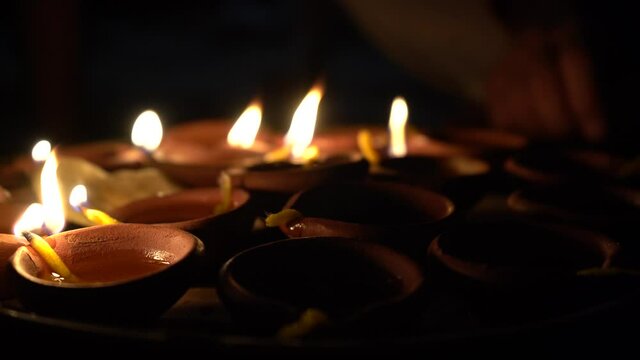 Hand lighting a diya oil lamp from another lit lamp on the hindu festival of diwali or showing the spreading of a message or hope as one flame provides and shares light