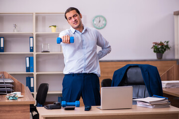 Young male employee doing physical exercises at workplace