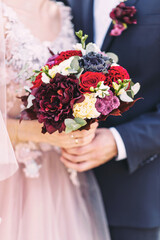 Beautiful wedding bouquet in the hands of the bride and groom