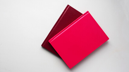 Colored notepads (pink and red) on a white background. Office. Top view, flat lay, minimal workspace.