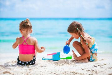 Two little happy girls have a lot of fun at tropical beach playing together