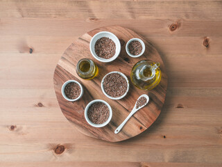 Obraz na płótnie Canvas flax seeds and flaxseed oil on wooden table. Set of small bowls with organic flax seed or linen seed. Flax oil is rich in omega-3 fatty acid. Copy space. Top view or flat-lay.