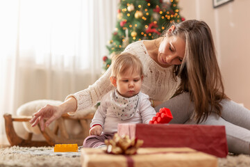 Mother and baby boy opening presents and playing with toys for Christmas