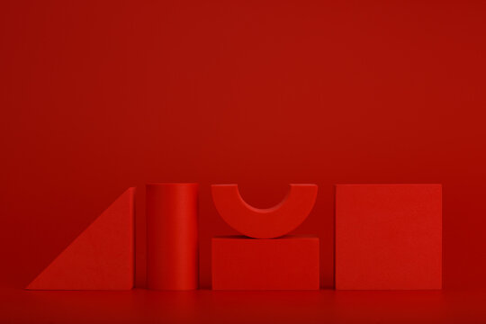 Red monochromatic still life with three-dimensional red geometric figures on a red background with a space for text