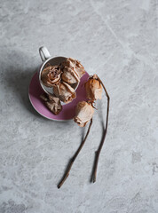 withered roses on a light background. Dried roses in a pink glass