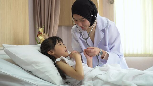 Arab doctor woman examining  girl patient body by stethoscope on bed in hospital
