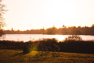 Ruhiges Seeufer mit Sonnenuntergang und Gras am Heiligen See mit Pärchen und Fahrrad - 395032017