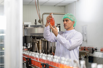Male specialist checking goods or product bottles. Male worker checking product of Basil seed with fruit on the conveyor belt in the beverage factory before shipment. Inspection quality control