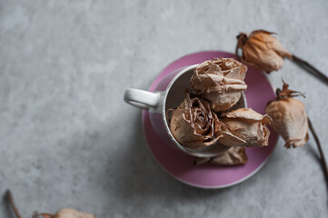 withered roses on a light background. Dried roses in a pink glass