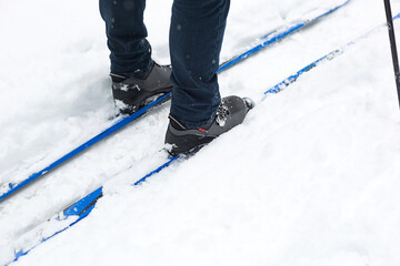 Feet of a skier in ski boots on cross-country skis. Walking in the snow, winter sports, healthy lifestyle. Close-up, copyspace