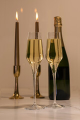 Selective focus of champagne glasses with two out of focus lit candles and a champagne bottle