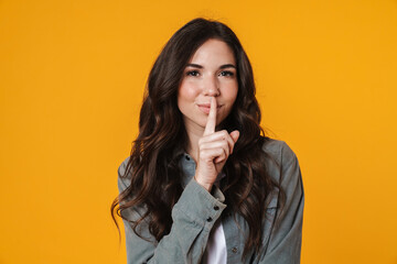 Pleased beautiful girl showing silence gesture on camera
