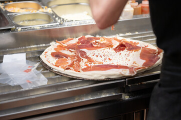 Young chef preparing a Serrano ham pizza