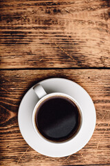Black coffee in white cup over wooden surface