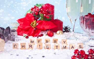 Christmas decoration with poinsettia flower, berries, red candles with text Merry Christmas with wooden words.