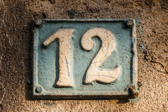Old retro weathered cast iron plate with number 12 closeup