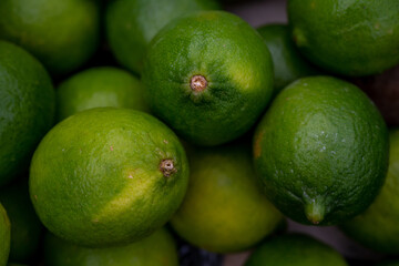 Fresh ripe green lemons in the market. Texture background, pile of lime for sale.