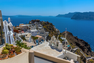 A view across roof tops in the village of Oia, Santorini towards the castle and the caldera beyond in summertime