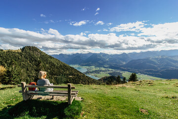 Fototapeta na wymiar Girl enjoying view of mountain panorama and Alpine lake,Austria.Backpacker relaxing on the summit.Active holiday freedom concept.Wanderlust travel scene.Quiet relaxation in nature.Positive energy.