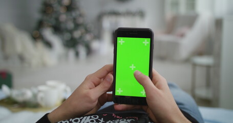 The boy uses a phone with a green background, Christmas atmosphere