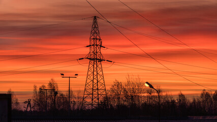 Sieć wysokiego napięcia na tle pomarańczowego wschodu słońca 