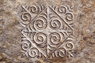 Ornamental print on the stone surface. Vintage ornament on the stone. Close-up seamless texture. Stone texture. Pattern on the stone. Embossed pattern. Wallpaper.