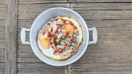 Top view picture of Vietnamese fried eggs in an aluminum dish placed on a wooden table.