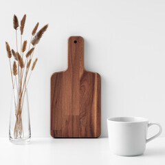 Mug transparent vase with dried flowers and a wooden board on a white background. Eco-friendly materials in interior decor, minimalism. Copy space, mock up.