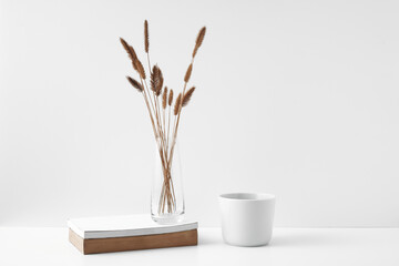Mug and transparent vase with flowers on a white background. Eco-friendly materials in the decor of the room, minimalism. Copy space, mock up.