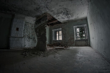 Fototapeta na wymiar An old and scary room in an old abandoned house. The ceiling is collapsing, the trees outside the windows. Dirty and dark.
