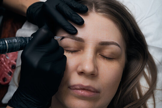 Permanent eyebrow makeup procedure. Eyebrow tattooing, process. The use of tools by a master for permanent eyebrow makeup.