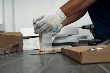 Furniture assembly process. Worker in overalls and white footwear. Joining pieces of furniture. Do it yourself.