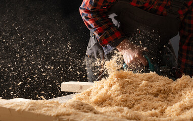 Planing wooden plank with a electric plane.