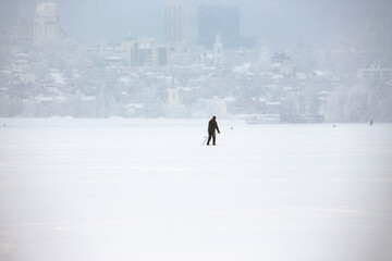 Silhouette of a lone skier on the background of the city in a snowfall. An active lifestyle in any weather.