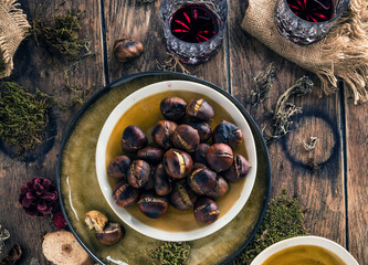 Roasted chestnuts for Christmas served on a wooden table with red mulled wine
