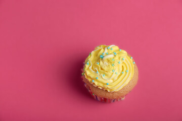cupcake with yellow cream on a pink background.