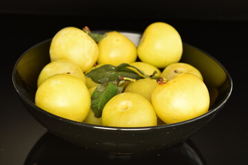 Several organic yellow plums, close-up, on a black background.