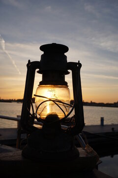 Oil lamp lit by sunset over coastal landscape