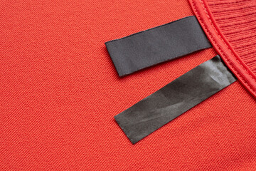 Blank black laundry care clothes label on red fabric texture background