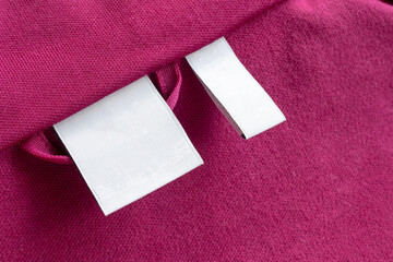 Fototapeta premium Blank white laundry care clothes label on red fabric texture background