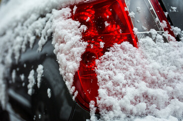 First snow. Late fall. The rear headlight of the car is covered with fluffy snow.