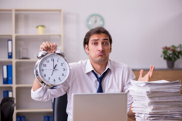 Young male employee in time management concept in the office