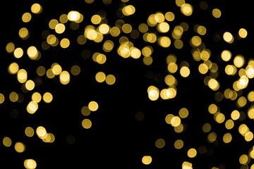Defocused bokeh christmas small gold lights on black background. Blurred abstract gold glitter texture. Gold bokeh glitter wallpaper for Christmas, New year, festival background.